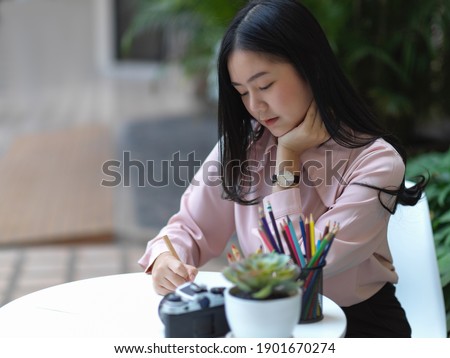 Portrait of female student concentrating on her drawing on coffee table in cafe