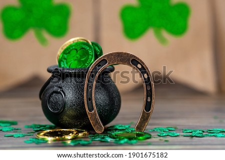 Background for St. Patrick's Day, March 17, with a lucky horseshoe, clover and a pot of gold on a wooden background.