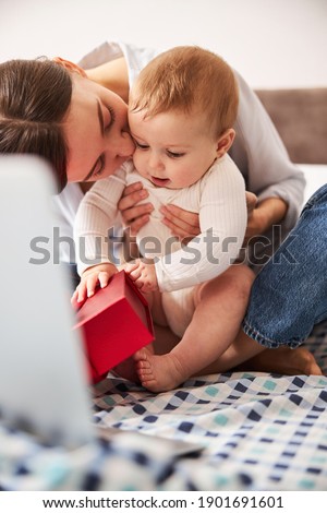 Busy child stretching hands while trying to open red box, feeling love of mother
