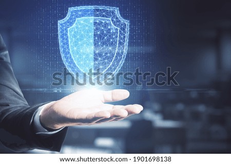 Hand holding creative digital shield on blurry background. Internet safety concept.