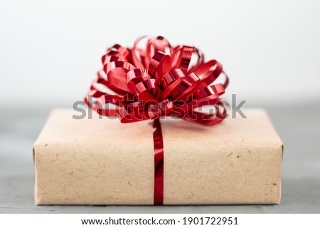 present box in craft paper with red bow on grey background
