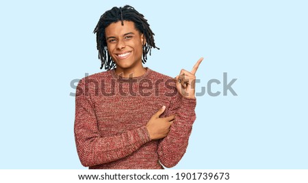 Young african american man wearing casual winter sweater smiling happy pointing with hand and finger to the side 