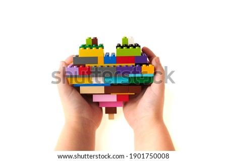 colored heart with baby building blocks in the hands of a child isolated on white background