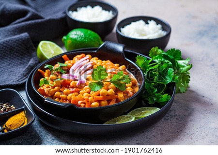 Vegan chickpea curry with rice and cilantro in a black bowl, dark background. Indian cuisine concept. Royalty-Free Stock Photo #1901762416