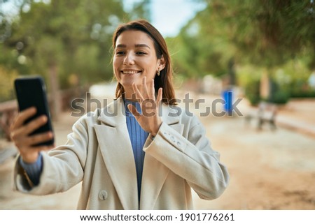 Young hispanic woman smiling happy doing video call using smartphone at the park.