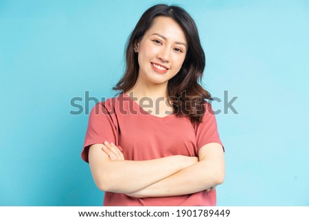 Beautiful asian woman with arms crossed over blue background
 Royalty-Free Stock Photo #1901789449
