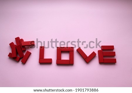 Wooden red bars and the inscription love of them on a pink background