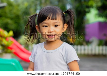 Portrait​ image of​ 2-3​ years old​ baby​ toddler. Face of smiling​ Asian​ girl in head shot. Happy​ kid playing​ at the park playground. In summer or spring​ season Royalty-Free Stock Photo #1901794150
