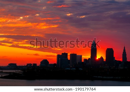 The rising sun peeks out from behind nearly silhouetted buildings of downtown Cleveland Ohio
