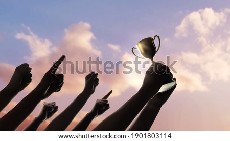 Teamwork, Winning, Goal and Successful Concept.  Silhouette of People Raise Up Hands into the Sky. the Leader Holding a Golden Trophy. Cheerful Gesture Hand Royalty-Free Stock Photo #1901803114