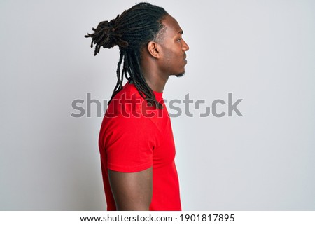 African american man with braids wearing casual clothes looking to side, relax profile pose with natural face with confident smile. 