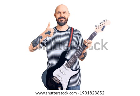 Young handsome man playing electric guitar smiling happy and positive, thumb up doing excellent and approval sign 