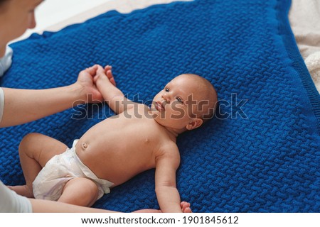 Gymnastics baby. woman plays and doing exercises with child for its development. massage a small newborn baby, does exercises on the arms. Baby Massage,mother Hand Massaging Hand Of Her Baby.