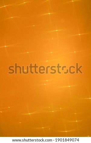 orange abstract background with blurred quadrilateral rays asterisks highlights and flare