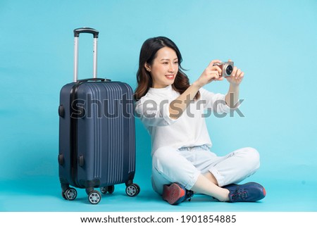 Beautiful Asian woman sitting posing beside suitcase and preparing for travel
