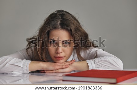 Tired bored teen girl upset by difficult learning looking at books stack stressed by exam test preparation, overwhelmed student exhausted with too much study homework cram, boring education concept