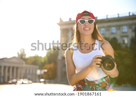 Young photographer with professional camera outdoors. Space for text