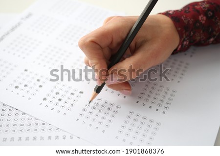 Female hand holds pencil and marks answers to test. Hiring Testing Concept