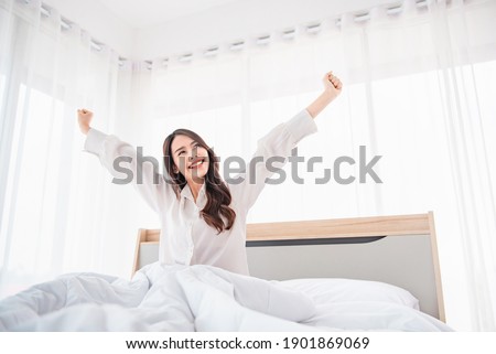 Happy asian woman stretching hands in bed after wake up in the morning, Concept of a new day and joyful weekend. Royalty-Free Stock Photo #1901869069