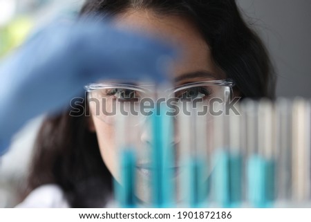 Portrait of woman in glasses who looks at test tubes with liquid. Research and development concept Royalty-Free Stock Photo #1901872186