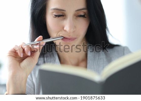Woman with sly eyes looks at diary. Successful women in business concept