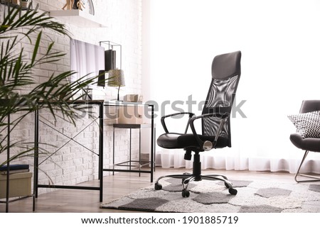 Comfortable chair near desk in modern office interior Royalty-Free Stock Photo #1901885719