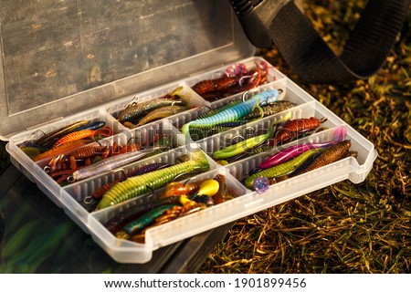 Fishing tackles and fishing baits in box .Classic Colored Fishing Lure , Beautiful Background digital image.Fishing on the lake at sunset. 