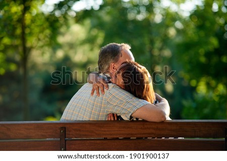 Hugging mature couple on the bench. Man and woman in the park.