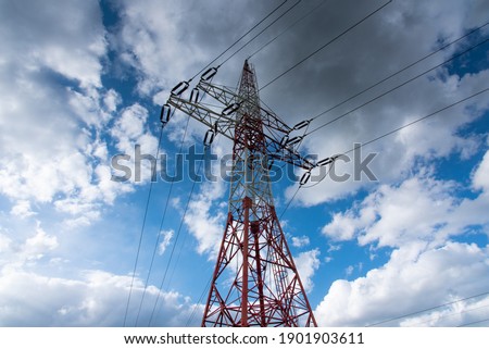 Electric power line, pre-storm sky with dramatic fluffy clouds. Red and white high voltage power line pylon. 