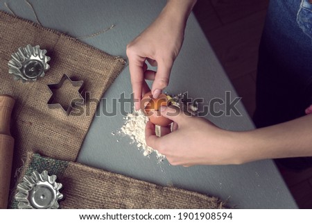 Female hands break a chicken egg into flour