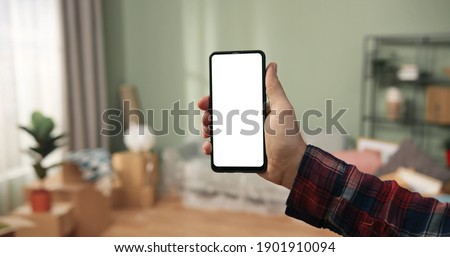 Close up of male hands holding black smartphone with blank screen in living room. Cellphone display with with blank screen. 