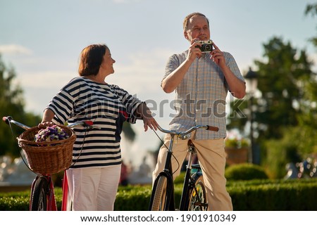 Happy mature tourists with vintage photo camera. Loving couple outdoors in the park.
