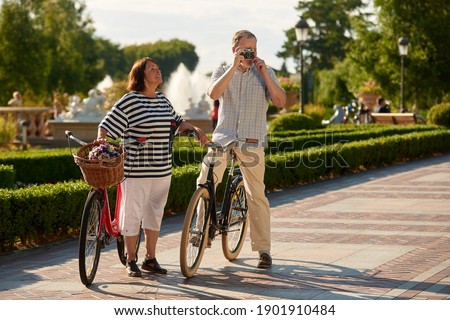 Retired married tourists with bikes and photo camera. Loving senior couple outdoors in the park.