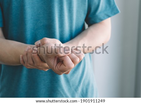 male arms holding his painful wrist caused by prolonged work on the computer, laptop,neurological disease concept. Numbness of the hand