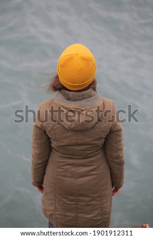 a young girl walks by the sea on a cloudy day