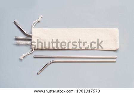 Reusable stainless steel straws and cleaning brush with cream cotton bag on grey background. Eco friendly lifestyle concept Royalty-Free Stock Photo #1901917570