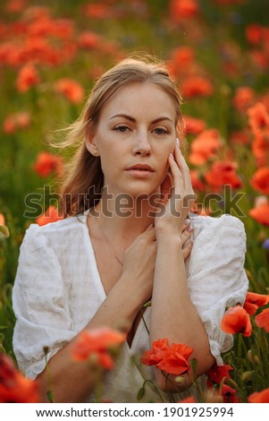 portrait of a girl in a white dress in a field of red poppies