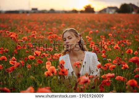 portrait of a girl in a white dress in a field of red poppies