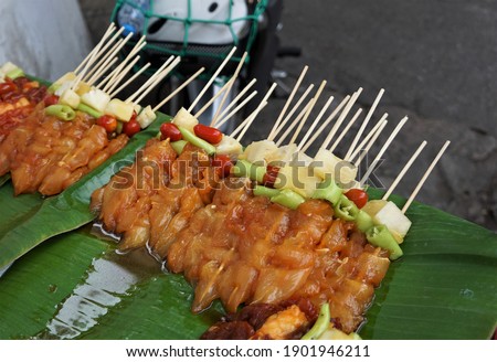 Bulk raw barbecues are stacked on banana leaves. It's at the street food store.