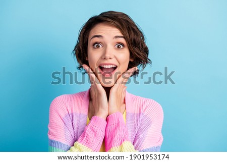 Photo portrait of excited girl with open mouth touching face with two hands isolated on pastel blue colored background