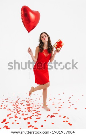 Happy beautiful girl posing with heart balloon and gift box isolated over white background