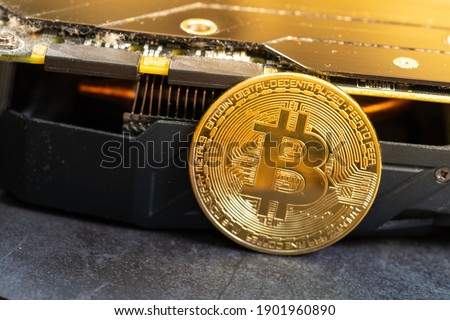 A close up of golden bitcoin placed in front of the graphic card heat sink.