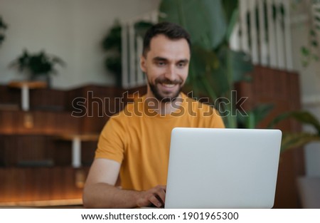 Handsome man freelancer working online, typing, searching information. Copy space. Blurred image of businessman using laptop computer, watching training courses, focus on laptop