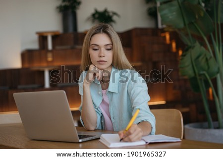 Pensive businesswoman using laptop computer, taking notes, working project. Student studying, distance learning, exam preparation, education concept 