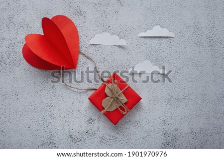 Flat lay Happy Valentine's Day photography with gift box and paper origami heart in air balloon shape. Cute romantic greeting card. 