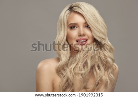 Blonde woman with long curly beautiful hair, studio shot on beige isolated with free copy space.