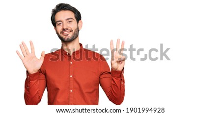 Young hispanic man wearing casual clothes showing and pointing up with fingers number eight while smiling confident and happy. 
