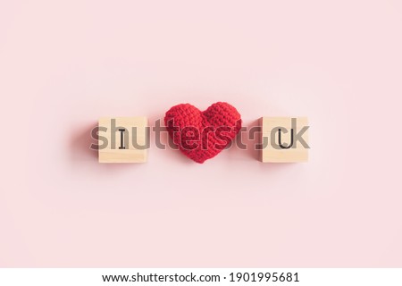 Wooden block with "I love you" and red heart on pink background, Valentine's Day concept