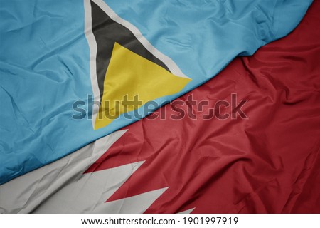 waving colorful flag of bahrain and national flag of saint lucia. macro
