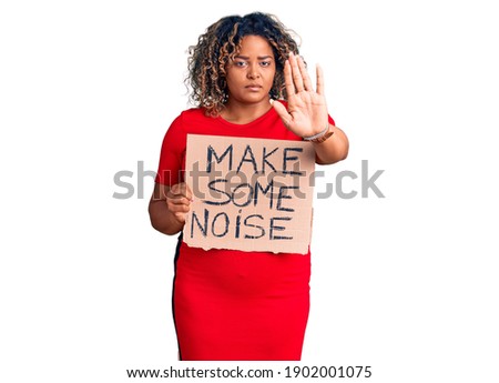 Young african american plus size woman holding make some noise banner with open hand doing stop sign with serious and confident expression, defense gesture 